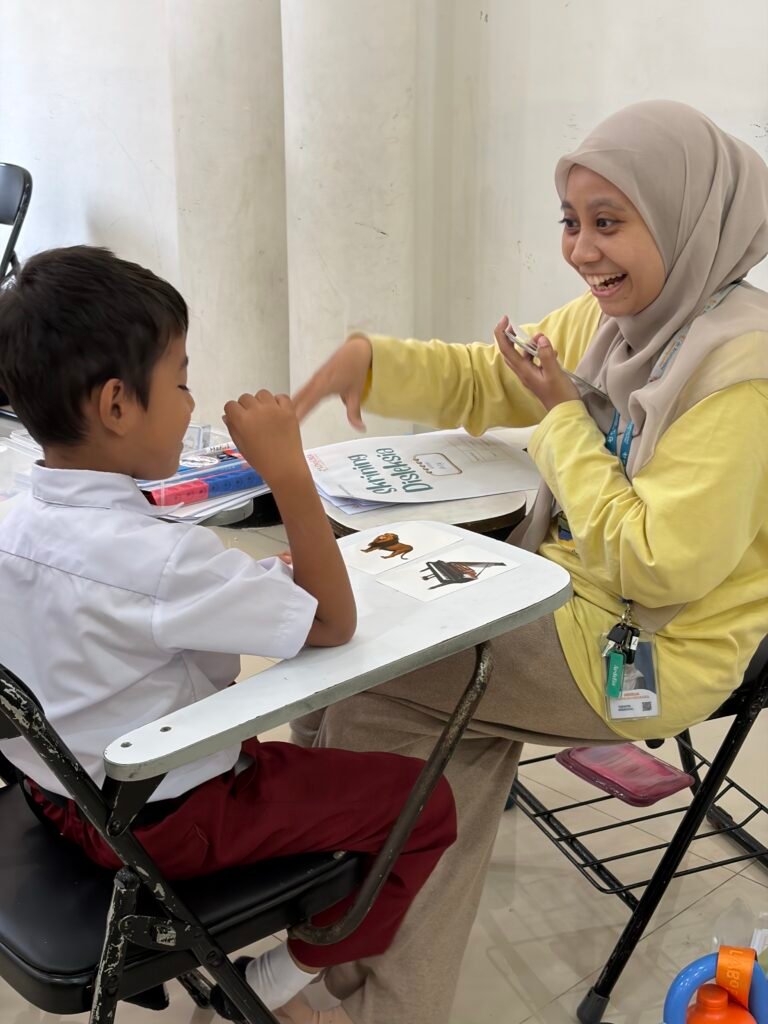 Pengampu dari dKLC dan ADI sedang berinteraksi dengan siswa yang di skrining secara menyenangkan.